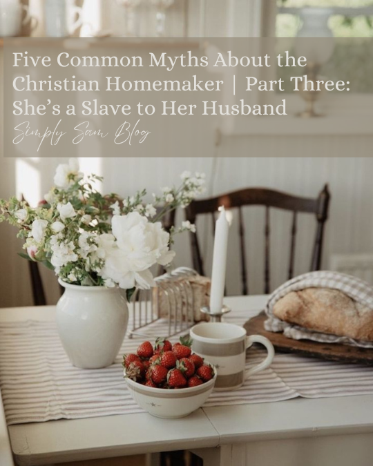 Farmhouse table with strawberries, flowers, and fresh bread with the words "Five Common Myths About the Christian Homemaker | Part Three: She's a Slave to Her Husband."